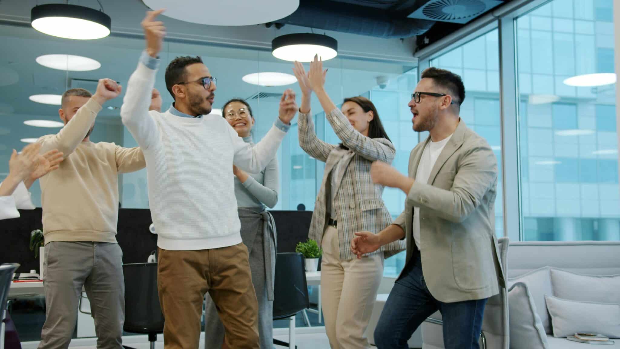 Équipe souriante célébrant dans un bureau moderne — attitude positive en entreprise